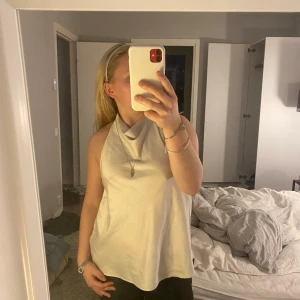 Fest topp - Fin krämvit festtopp med halterneck och knyte i bak.