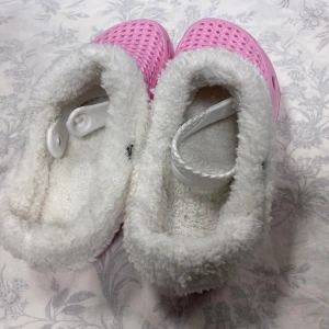 Vinter / Sommar tofflor med foder - Supermysiga rosa tofflor med vitt fluffigt foder. Perfekta för att hålla fötterna varma och sköna. De har en praktisk rem för bättre passform och en mönstrad sula för bra grepp. Perfekta för kalla dagar hemma ,                        Storlek kvar 36 , 38 , 39      Tjocka fleece inuti , rekommenderar att välja 2 Stlk större än som i vanlig. Till exempel storlek 39 passar som storlek 37 i vanligt 