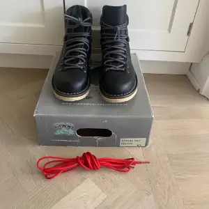 Säljer ett par snygga svarta boots från Diemme i mycket bra skick. De har en robust design med grå snörning och en ljus sula som ger bra grepp. Perfekta för höst och vinter! Extra röda skosnören medföljer för en personlig touch. Passar både till vardags och lite tuffare terräng.