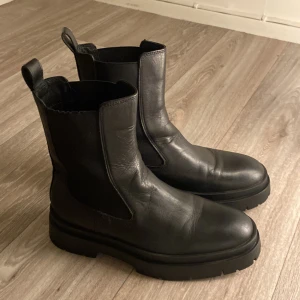 Svarta boots från Zara - Säljer ett par svarta boots från Zara i skinn. De har en chunky sula och är perfekta för höst och vinter. Bootsens stilrena design gör dem lätta att matcha med olika outfits. De är i mycket bra skick och redo för nya äventyr!