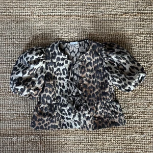 Leopardmönstrad topp från Ganni - Säljer en superfin ”viral” leopardmönstrad topp från Ganni i storlek 34. Den har puffiga ärmar och en söt volangdetalj i midjan. Perfekt för en snygg look! 🐆