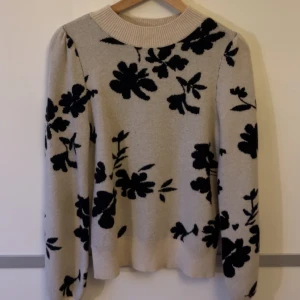 Stickad tröja - Säljer denna fina tröja från vila. Beige med svarta blommor på. Jättefin och bra skick men kommer inte till användning längre tyvärr🥰