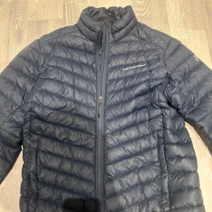 Blå dunjacka från Peak Performance - Säljer en snygg blå dunjacka från Peak Performance. Den är perfekt för kyliga dagar med sin quiltade design och dragkedja framtill. Jackan har en hög krage för extra värme och är i väldigt bra skick. Passar perfekt för höst och vinter! Köpte den för nått år sedan för runt 3000kr och den är sparsamt använd. (Storleken är L men passar även perfekt för M. Och pris kan diskuteras lite… Skriv för mer info