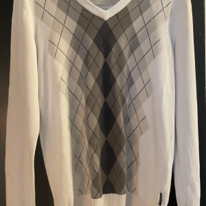 Vit tröja med argylemönster från Peak Performance - Säljer en stilren vit tröja från Peak Performance i storlek S. Den har ett klassiskt argylemönster i grå och svarta nyanser på framsidan. Tröjan är långärmad och perfekt för både höst och vår. Passar lika bra till vardags som till lite finare tillfällen. 🖤