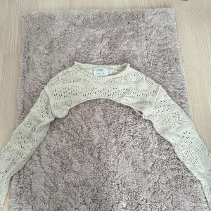 Beige stickad bolerotopp från Zara - Säljer en superfin beige stickad bolerotopp från Zara. Perfekt för lager-på-lager looken! Den har ett snyggt stickat mönster och långa ärmar. Passar perfekt till både vardag och fest. 🧶✨