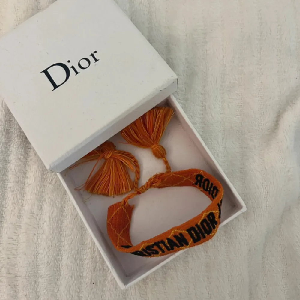 Orange Dior armband. Orange med svart skrift. Skick: 10/10, som ny. Kontakta oss för fler bilder eller info!🙌. Accessoarer.