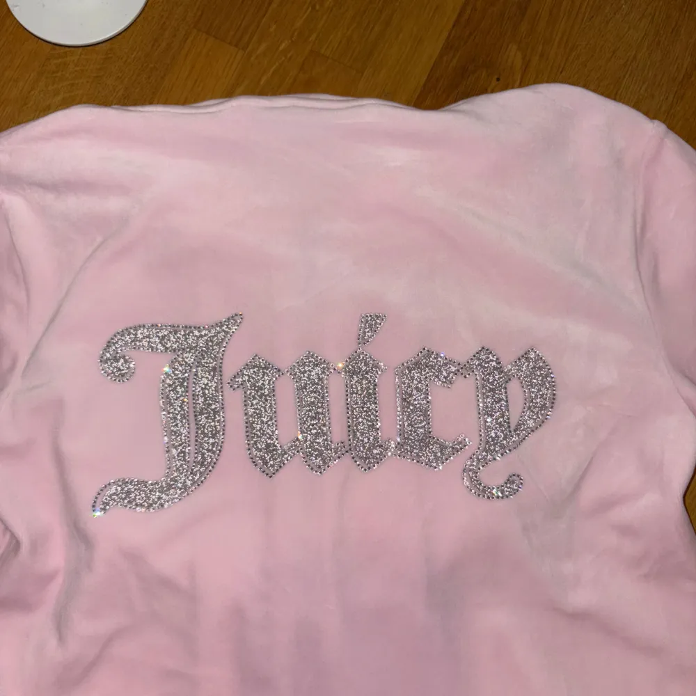 Säljer ett supermysigt rosa velourset från Juicy Couture. Hoodien har dragkedja och en glittrig 'J' på bröstet, medan byxorna har 'Juicy' i glitter på baksidan. Perfekt för chill dagar eller när du vill känna dig extra glam. Setet är i bra skick och redo för nya äventyr! 💖Vid snabb affär går priset att förhandla!. Övrigt.