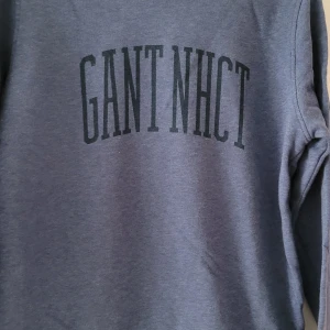 Blå tröja från GANT - Säljer en snygg blå tröja från GANT i storlek XS. Den har en stilren design med texten 'GANT NHCT' tryckt på framsidan. Perfekt för en avslappnad stil och passar bra till både jeans och chinos. Tröjan är i mycket bra skick och redo för nya äventyr!