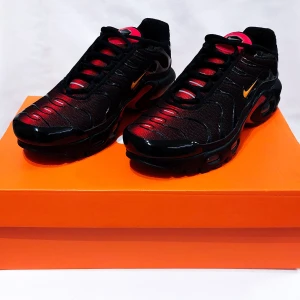 Nike Air max Plus TN  - Snygga Nike sneakers i svart och rött med cool design och orange detaljer. Perfekta för både träning och vardag. Skorna har en bekväm passform och är i mycket bra skick. Sula med bra grepp och stilren look. Passar perfekt för dig som vill ha en sportig stil med en touch av färg.