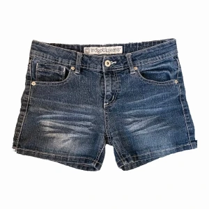 Blå jeansshorts från Indigobluejeans - Snygga blå jeansshorts från Indigobluejeans i mycket bra skick. De har en klassisk femficksdesign och coola korsdetaljer på bakfickorna. Perfekta för sommardagar eller en avslappnad vårlook. Midjan är normal och de har en knapp och dragkedja framtill. Orginal pris: ca.299 (2.99 dollar)