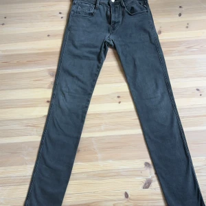 Mörk Grå Replay Anbass  - Säljer ett par Mörkgrå Replay Anbass i mycket bra skick. De har en slim passform och är perfekta för både vardag och fest. Jeansen har en klassisk femficksdesign och stängs med dragkedja och knapp. Materialet är mjukt och bekvämt, vilket gör dem till ett måste i garderoben. Jeansen har ett litet litet hål, se 4 bild