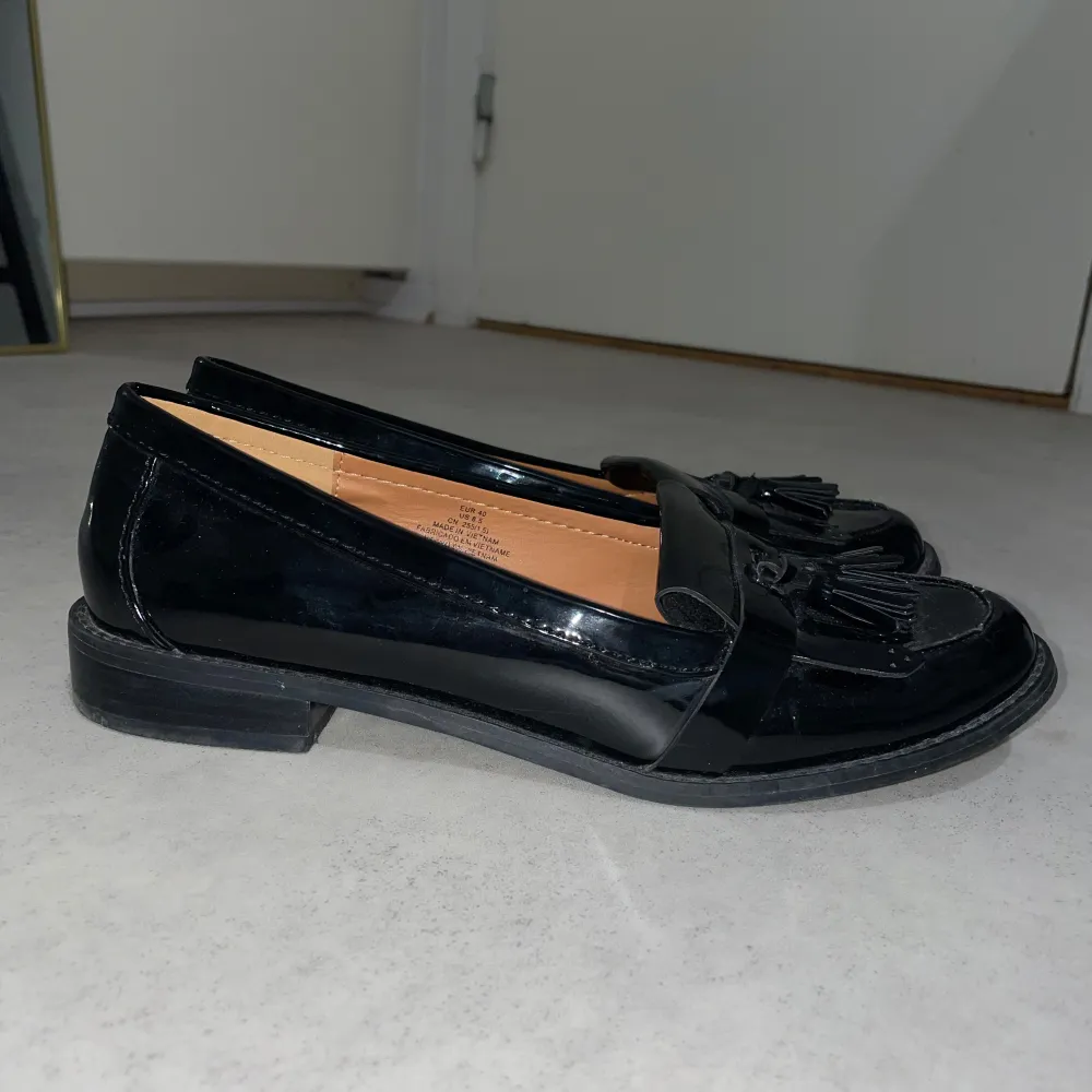 Snygga svarta loafers i skinn med dekorativa tofsar på ovansidan. Perfekta för både vardag och festliga tillfällen. De har en klassisk design med låg klack och en bekväm passform.. Skor.