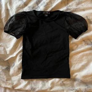 Svart topp med puffärmar - Snygg svart t-shirt med puffiga ärmar i prickigt mönster. Toppen har en normal passform och är tillverkad i ett mjukt material💞