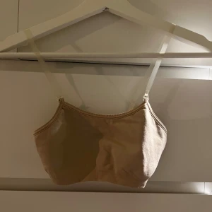 Beige träningstopp från GK Elite - Säljer en beige linnetopp från GK Elite. Toppen är i ett mjukt och stretchigt material med smala axelband. Perfekt för en avslappnad stil.