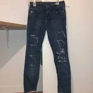 Blå skinny jeans från Zara - Snygga blå skinny jeans från Zara med slitna detaljer. De är lågmidjade och har en klassisk femficksdesign. Perfekta för en trendig och avslappnad look. I slutet av byxorna har de snygga slits som passar med allt! Mycket bra skick!! 