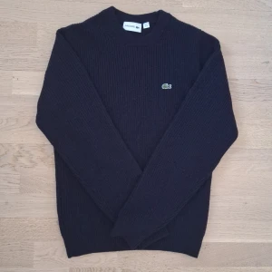 Svart stickad tröja från Lacoste - Säljer en snygg stickad tröja från Lacoste. Den är i väldigt bra skick och I storleken XS. Priset går att diskutera, så meddela gärna om du är intresserad ✅️