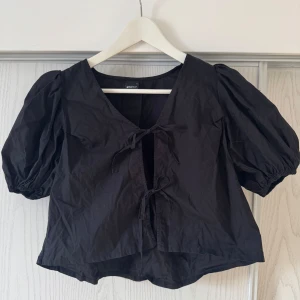 Svart blus från Gina Tricot - Snygg svart blus från Gina Tricot med puffiga kortärmar och knytning framtill🩷