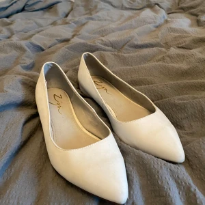 Vita ballerinaskor med spetsig tå - Säljer ett par eleganta vita ballerinaskor från Zign. Skorna har en stilren design med spetsig tå, perfekt för en chic look. De är bekväma och lätta att bära hela dagen.