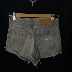 Lågmidjade shorts - Snygga  jeansshorts från Divided med slitna detaljer och fransig kant. Perfekta för en avslappnad stil. De har en klassisk femficksdesign och knappgylf.