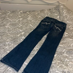 Low Waist Bootcut Stitch Jeans - Säljer dessa populära och snygga jeansen från Nelly, jeansen är bootcut och har dekorativa sömmar på bakfickorna. De är låg midjade och stängs med dragkedja och dubbla knappar. Jeansen är endast använda 2 gånger och är i väldigt bra skick.