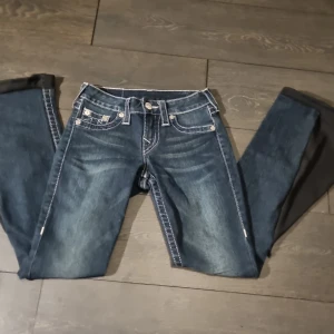 Blå jeans från True Religion - Skit snygga mörkblå jeans från True Religion med broderad detalj på bakfickorna. Säljer då de har blivigt för korta😔Använda ganska mycket. De är flare/bootcut💕Jag kan även tänka mig att byta mot ett par Miss me jeans eller ett par True religion jeans i storlek 24-25❤️(skickar inte bild på då de är för små)Pris kan diskuteras🫶🏼‼️Jag kan även tänka mig att byta mot ett par andra true religion jeans‼️Skriv innan köp för jag tar bara swich‼️Byxorna har två hål vid sömnen men det går enkelt att sy ihop🫶🏻