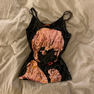 Svart paljettlinne med motiv - Snyggt svart linne med tunna axelband och ett iögonfallande paljettmotiv i rosa och guld.  Står XL i storlek men toppen är i XS