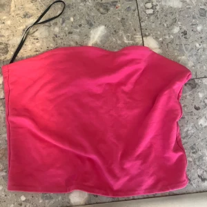 Rosa tubtopp - Snygg rosa tubtopp med enkel design. Perfekt för sommardagar eller som ett lager under en jacka. Den har en elastisk kant för att sitta på plats.