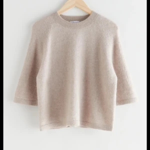 Other stories tröja - Säljer en stilren beige stickad tröja med trekvartsärm. Perfekt för lager-på-lager under kyligare dagar. Enkel design som passar till det mesta.