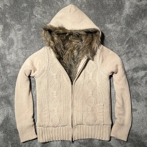 Stickad fodrad cardigan - Mysig beige stickad jacka med huva och pälsfoder. Riktigt skön att ha på sig och värmer bra, väldigt fint skick! Hör av er vid minsta fråga! BVSA!!!