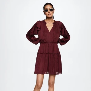 Vinröd klänning med volangdetaljer - Snygg vinröd klänning från mango med v-ringning och volangdetaljer. Klänningen har långa ärmar och en luftig passform. Endast använd en gång. Nypris ca 800kr