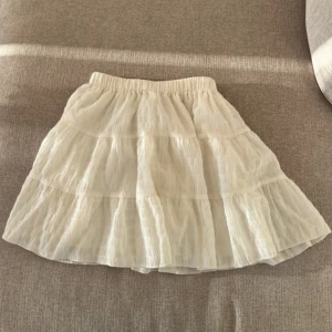 Vit kjol från Shein - Söt vit kjol från Shein med volanger. Perfekt för en somrig look. Den har en elastisk midja för bekväm passform.