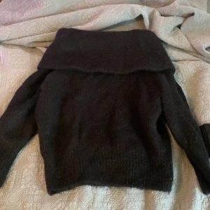 Svart offshoulder tröja från H&M - Säljer en svart offshoulder tröja från H&M. Tröjan har långa ärmar och en bred krage som ger en stilren look. Perfekt för kyligare dagar.