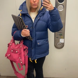 Blå vinterjacka från Fjällräven - Snygg blå dunjacka från Fjällräven med gula detaljer och en praktisk huva. Jackan är i nyskick och köpt förra vintern i butik! Köpt för 7000kr, säljer för 5000. Pris går att diskutera vid snabb affär 🥰storlek m men sitter perfekt på mig som brukar ha xs!