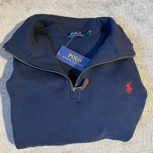 Helt ny Ralph lauren half- zip - Säljer en helt ny mörkblå half-zip från Ralph lauren, lappen/ tagen finns kvar. Den har långa ärmar och ett mjukt material på insidan. Passar bra när som helst. Jag köpte denna på plick men den passade tyvärr inte. Pris går att disskuteras