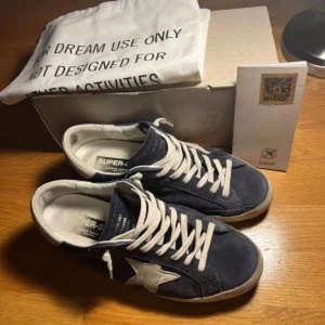 Blå sneakers med stjärndetalj - Snygga blå sneakers med vit stjärndetalj på sidan och vita snören. Perfekta för en avslappnad stil. Skorna har en klassisk design med en bekväm passform.