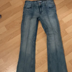 Blå bootcut jeans - Snygga blå bootcut jeans med hög midja och dubbla knappar. Perfekta för en avslappnad stil med en touch av retro. De har en klassisk femficksdesign och en lätt tvättad look. Storlek L, passar för M också. 