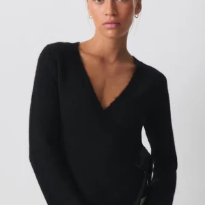Svart omlotttröja från Gina Tricot  - Snygg svart omlotttröja från Gina Tricot med knytning i sidan. Den har en v-ringad design och långa ärmar, perfekt för en stilren look. Passar bra till både jeans och kjol.💕