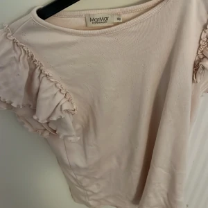 Ljusrosa topp från MarMar Copenhagen - Säljer en söt ljusrosa topp från MarMar Copenhagen. Toppen har korta ärmar med volangdetaljer som ger en romantisk touch. Perfekt för varmare dagar och kan enkelt matchas med olika outfits.