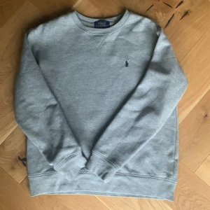  Ralph Lauren sweatshirt - Säljer en klassisk grå sweatshirt från Ralph Lauren med rund hals och det ikoniska broderade logotypen på bröstet. Perfekt för en avslappnad stil. Säljer för att den har blivit för liten. Passar ca 160-170 strl 14-16/ X. nypris: 1400 mitt pris: 490.  Väldigt bra skick.