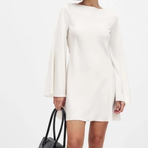 STUDENTKLÄNNING - Elegant vit klänning från NA-KD med lång ärm och öppen rygg. Klänningen är helt ny och oanvänd med lapp och förpackningen kvar. Perfekt för studenten eller examen! Storlek 34/XS