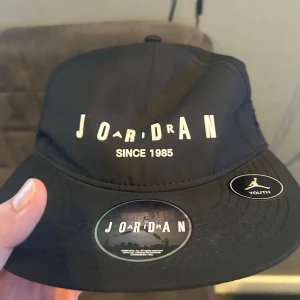 Svart keps från Jordan - Snygg svart keps från Jordan med broderad logga och texten 'Since 1985'. Kepsen har en justerbar passform och är märkt med 'Youth'. Perfekt för en sportig look.