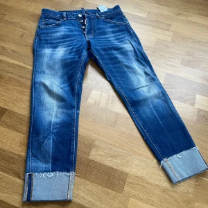 Blå jeans från Dsquared2 - Snygga blå jeans från Dsquared2, modell ”Skinny dan cropped jean ”. De har en croppad stil med uppvikta benslut och är tillverkade i Italien. Perfekta för en trendig look med slitna detaljer och klassisk femficksdesign.