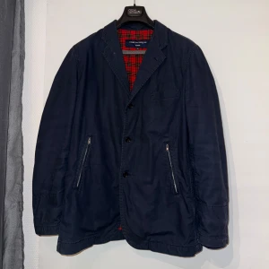 Mörkblå kavaj från Comme des Garçons junya watanabe - Säljer en stilren mörkblå kavaj från Comme des Garçons med röd- och svart-rutigt foder. Riktigt unik jacka som inte är lätt att få tag på. Står L men passar även M. Pris kan diskuteras