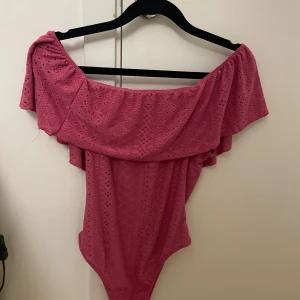 Rosa off-shoulder body - Jag säljer en rosa body med off-shoulder design och volangdetaljer. 