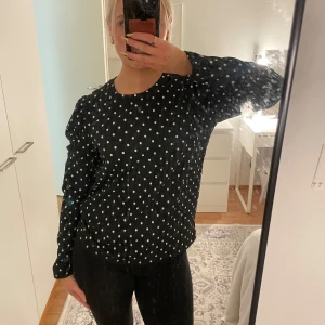 Svart prickig blus  - Säljer en stilren svart blus med vita prickar från märket Cubus. Blusen har långa ärmar och en rund halsringning. Perfekt för att ge en klassisk touch till din outfit. Passar bra till både jeans och kjol.