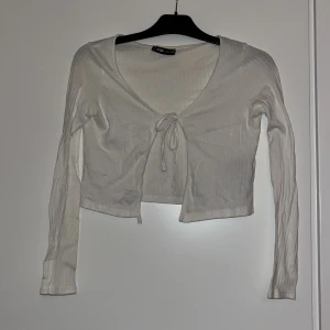 Vit ribbad bolerotopp - Vit ribbad kofta med snören som går att knyta. Från New Yorker🤍