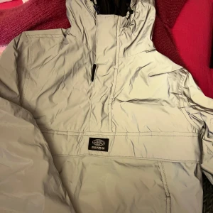 Reflex anorak vindjacka från Pull&Bear - Anorak jacka man trär över huvudet i reflex från pull & bear. Använd 1 gång. Dragkedja på ena sidan & resår på andra sidan. Ficka på magen med fleece inuti.   Perfekt på hösten/vintern när det är mörkt eller på promenader.  Kom gärna med prisförslag 🤍 Strl xs från pull & bear Säljer likadan i vit!!