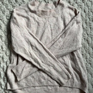 Rosa stickad tröja - Mysig rosa stickad tröja med rund hals och långa ärmar. Perfekt för kyliga dagar och ger en avslappnad stil. Tröjan har ribbade muddar vid hals och ärmslut.