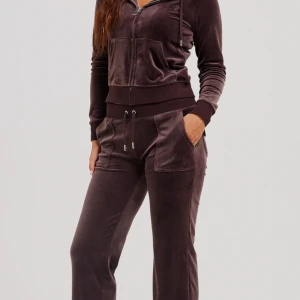 Brun velour hoodie från Juicy Couture - Säljer en snygg brun velour hoodie från Juicy Couture. Den har en dragkedja framtill och en praktisk känguruficka. Perfekt för en avslappnad stil med en touch av lyx. Passar perfekt till matchande byxor eller jeans.