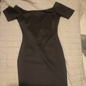 Svart klänning med korta ärmar off shoulder  - Elegant svart klänning med korta ärmar och en figurnära passform. Perfekt för en stilren look.